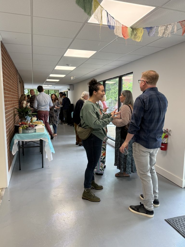 Community members gathered at the Quantic Wellness Collective Grand Opening in downtown Asheville, with prayer flags overhead